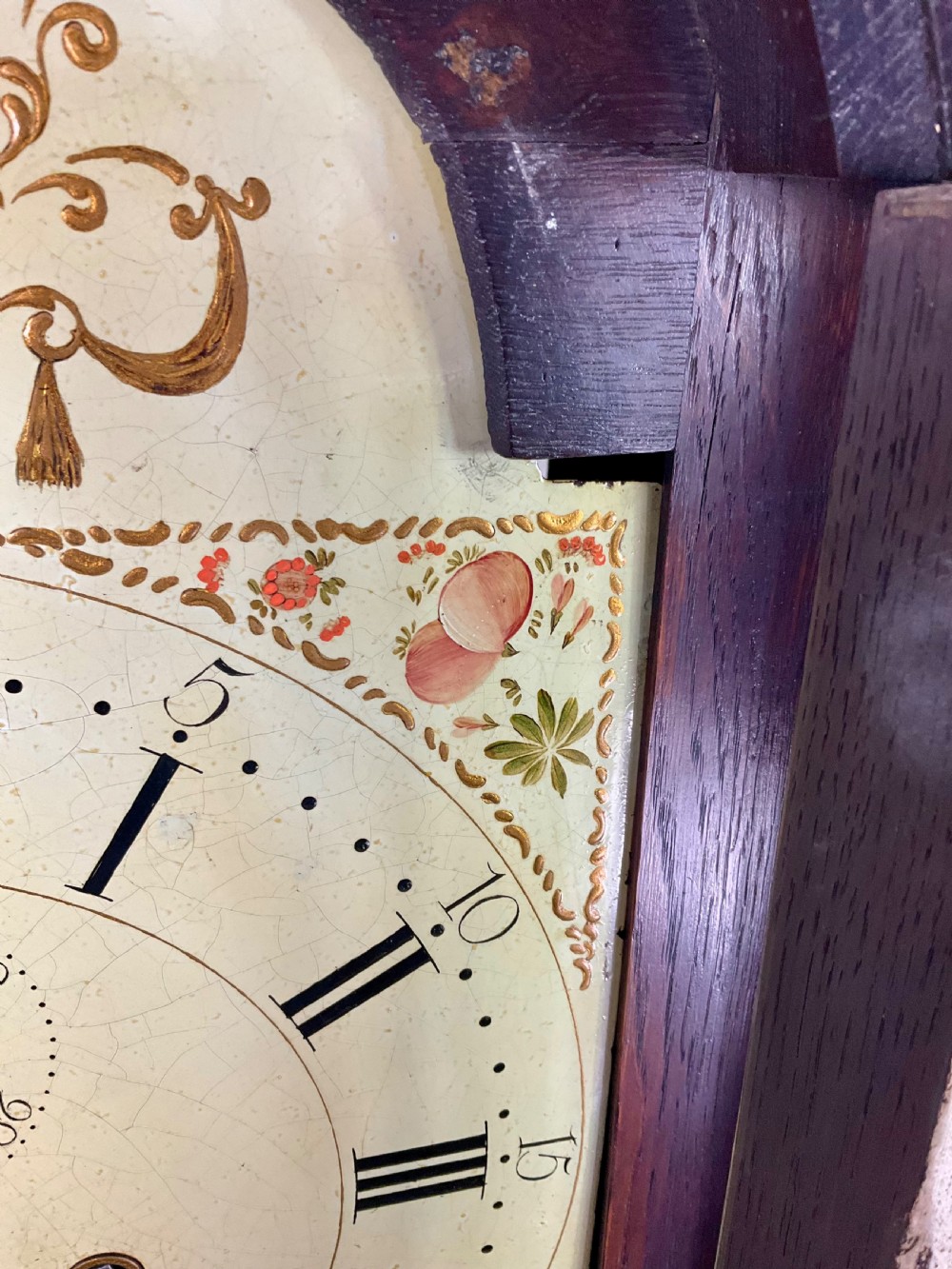 A dark oak Georgian longcase clock featuring a painted arched dial with Roman numerals and three brass urn finials on the bonnet. View VI