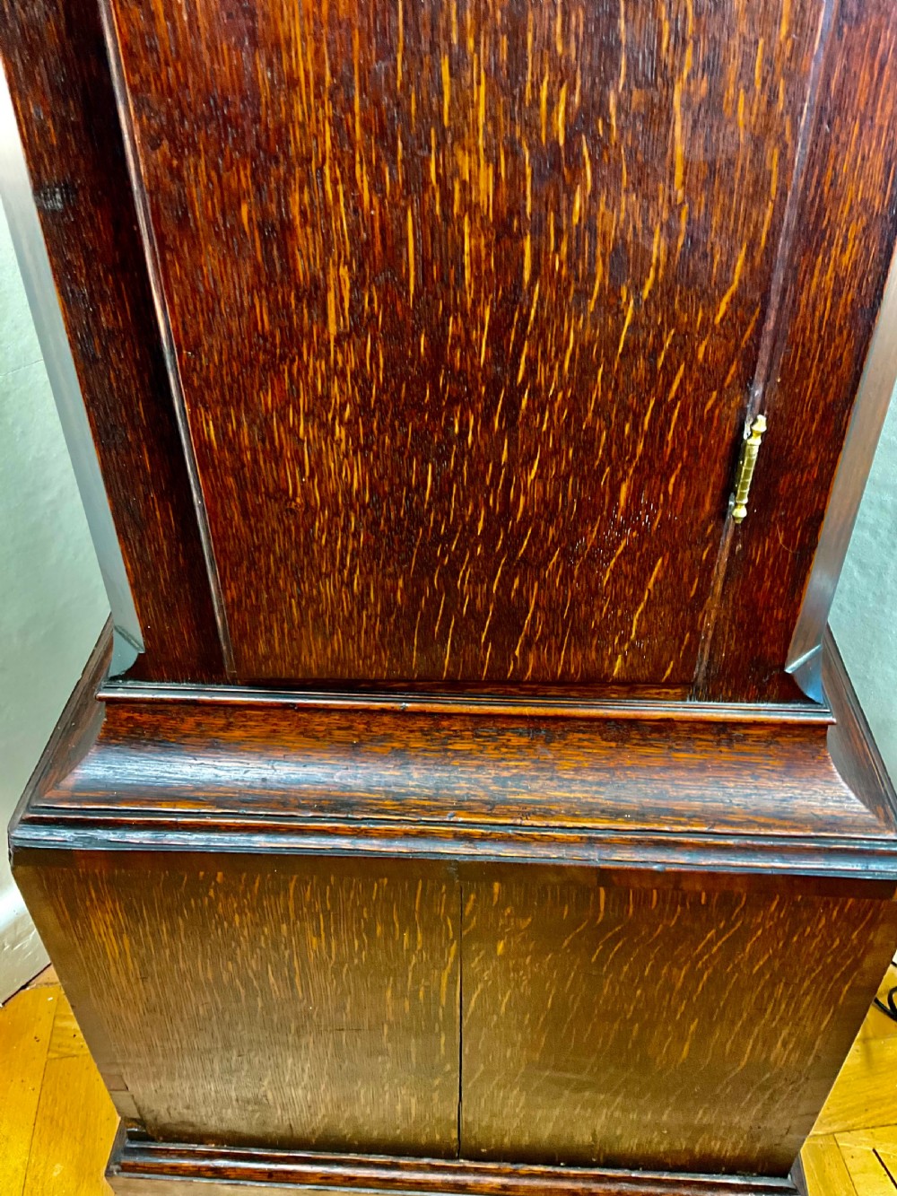A dark oak Georgian longcase clock featuring a painted arched dial with Roman numerals and three brass urn finials on the bonnet. View VIII