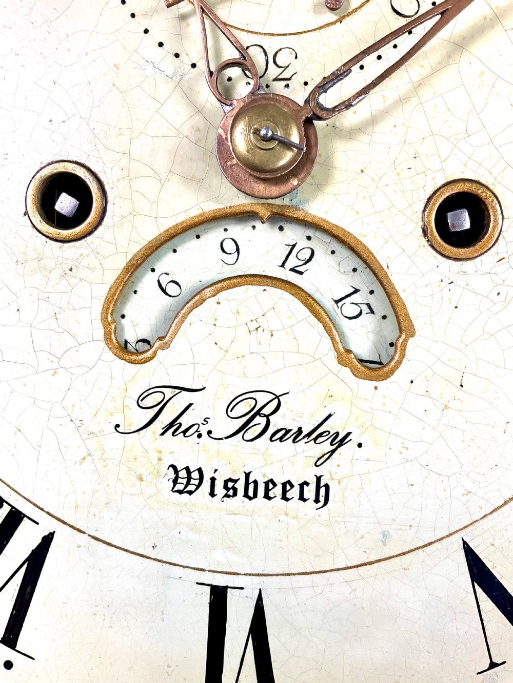 A dark oak Georgian longcase clock featuring a painted arched dial with Roman numerals and three brass urn finials on the bonnet. View XI