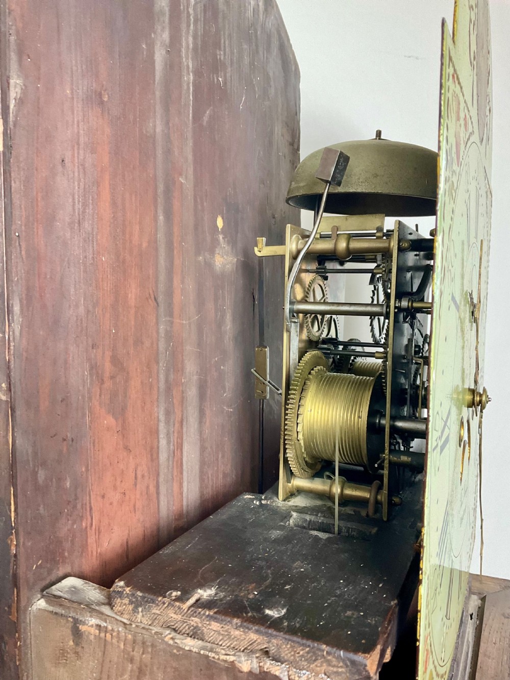 A dark oak Georgian longcase clock featuring a painted arched dial with Roman numerals and three brass urn finials on the bonnet. View XV