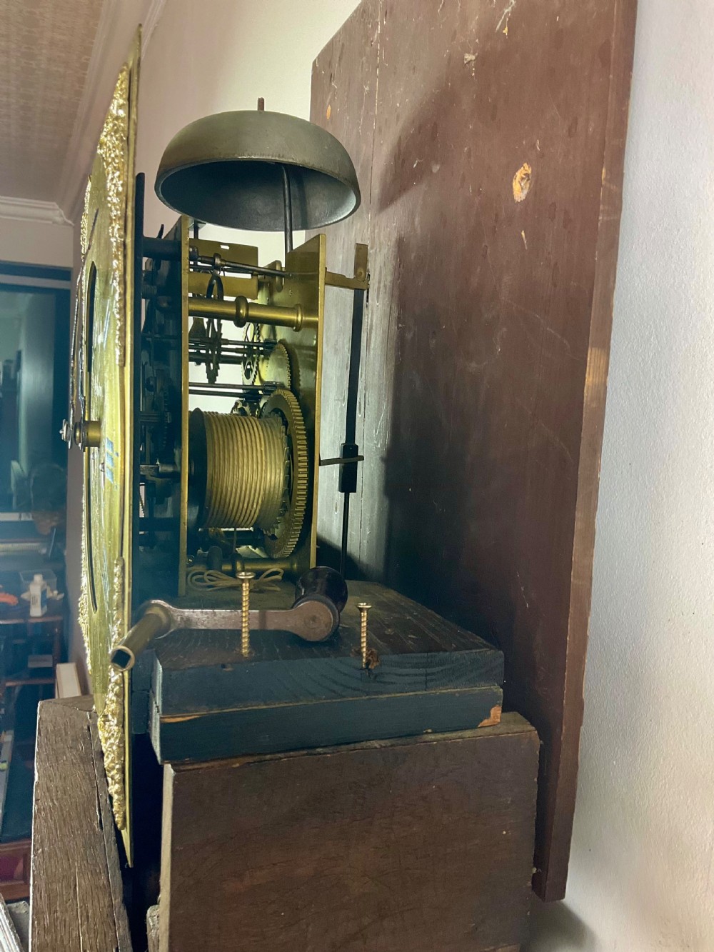 An Early Georgian oak longcase clock featuring a square brass dial with spandrels, flanked by turned columns, and a tall wooden trunk set on bracket feet. View X