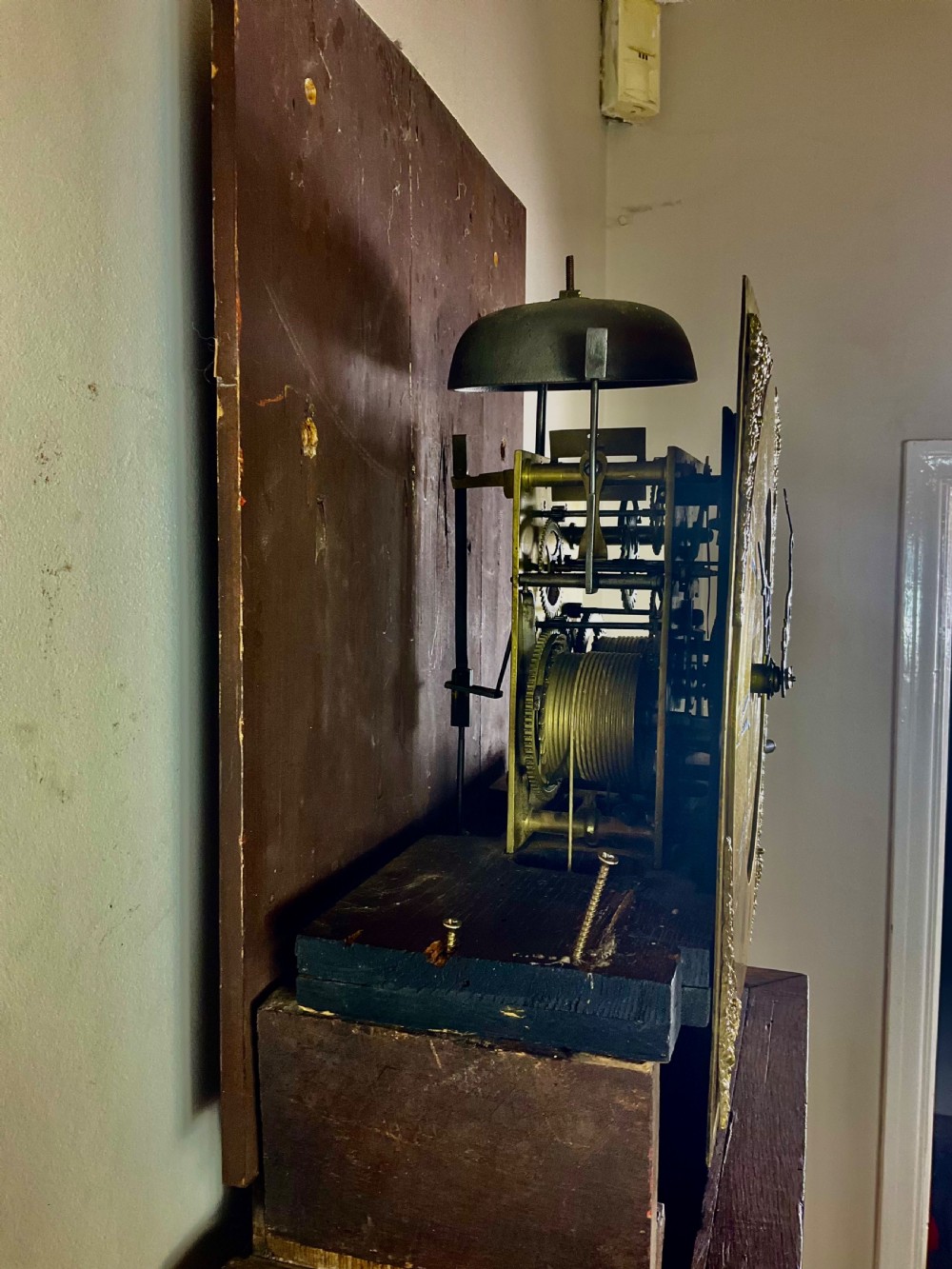 An Early Georgian oak longcase clock featuring a square brass dial with spandrels, flanked by turned columns, and a tall wooden trunk set on bracket feet. View XI