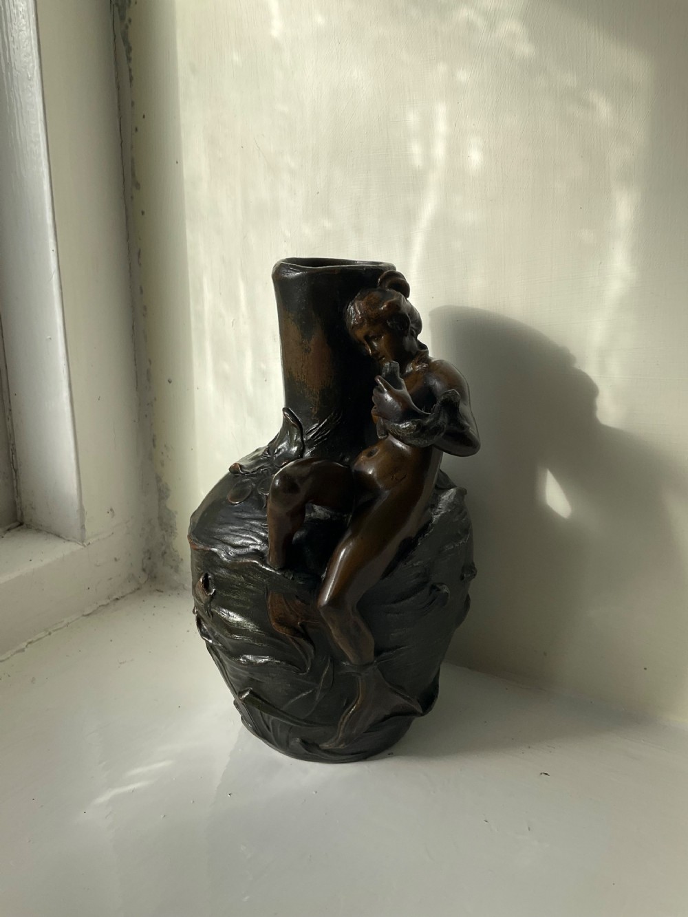 A dark patinated bronze Art Nouveau vase featuring a relief sculpture of a reclining female nymph on its side.
