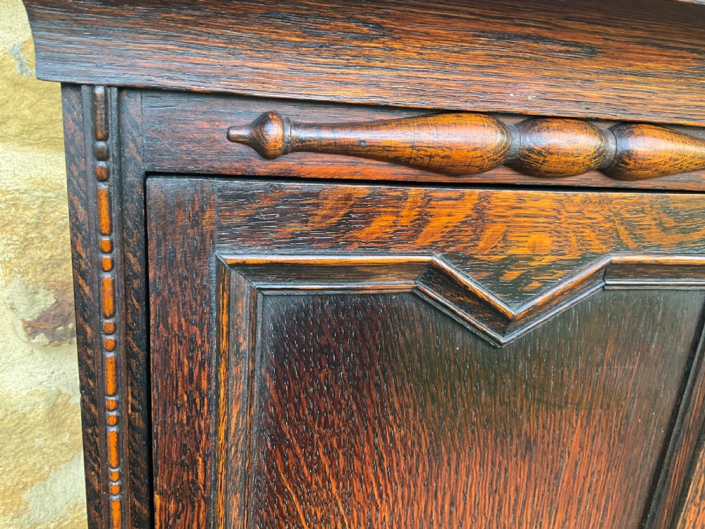 A dark oak longcase clock featuring an arched hood, silvered chapter ring dial, brass spandrels, and geometric inlaid trunk door. View IV