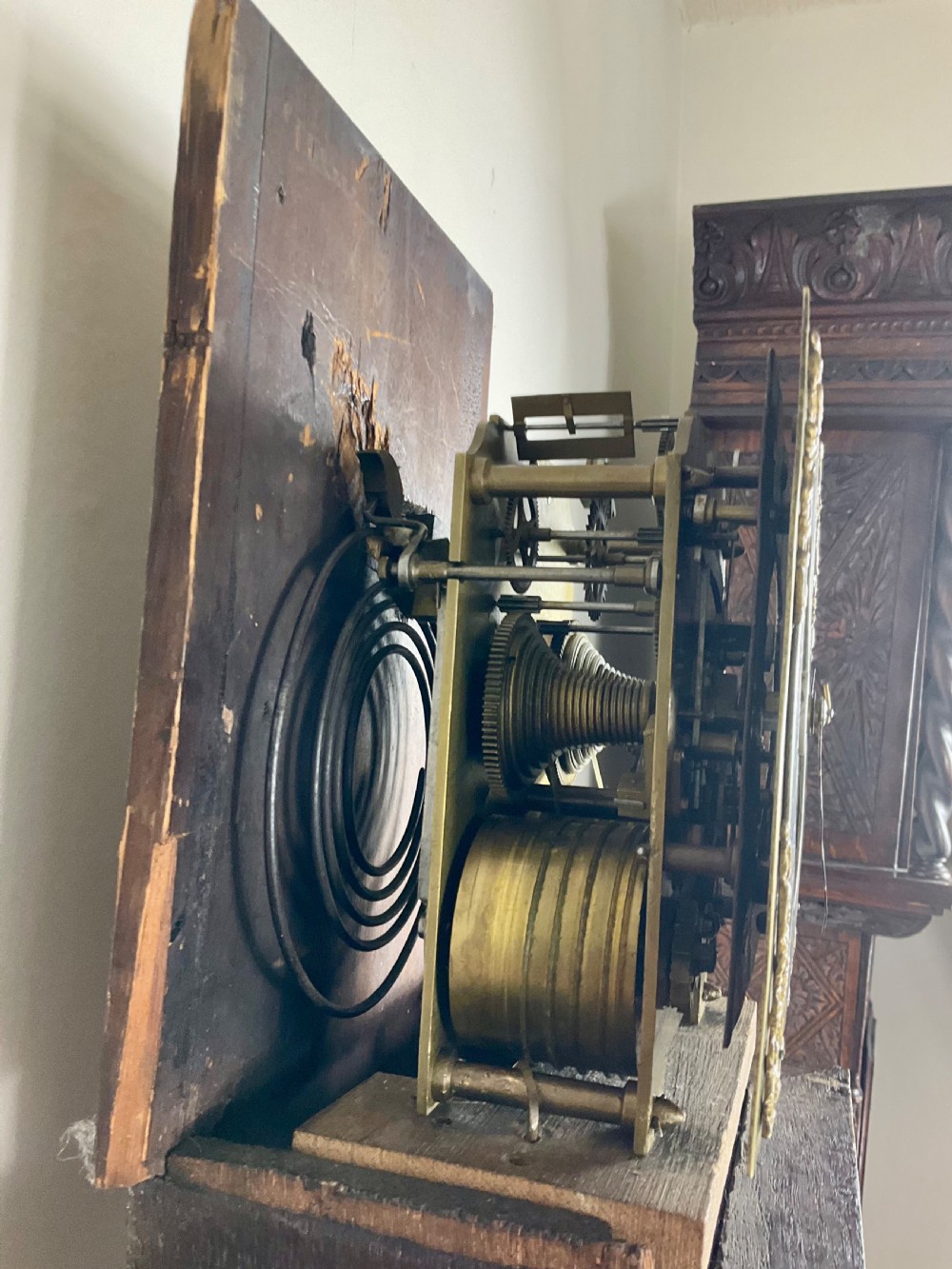 A slim Georgian oak longcase clock featuring a square brass dial with spandrels, fluted hood columns, a hinged trunk door, and a plinth base. View III