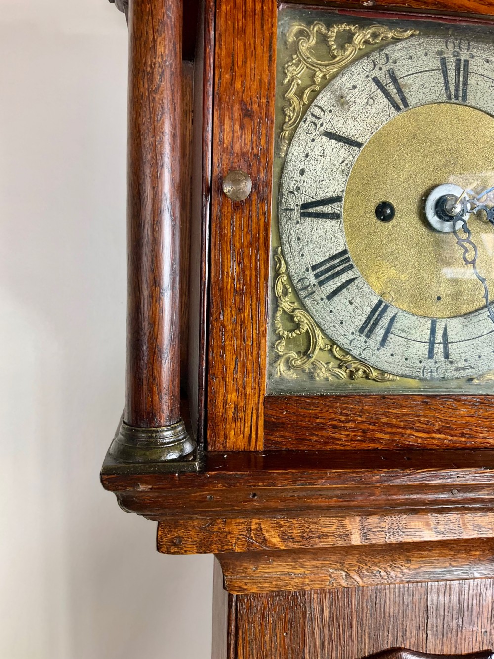 A slim Georgian oak longcase clock featuring a square brass dial with spandrels, fluted hood columns, a hinged trunk door, and a plinth base. View VIII