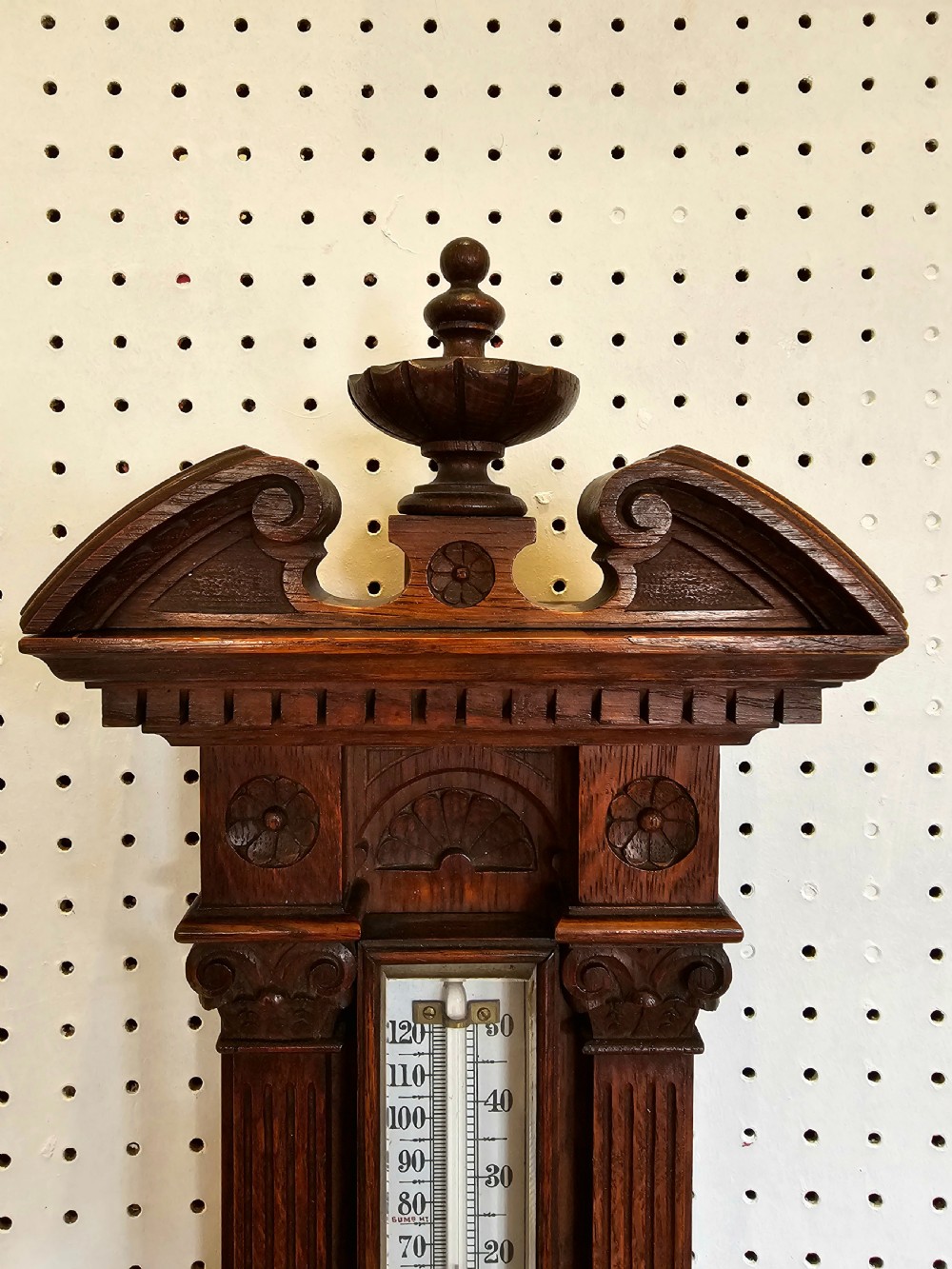 A carved oak Victorian wall barometer with an upper glass thermometer and a lower circular aneroid dial. View III