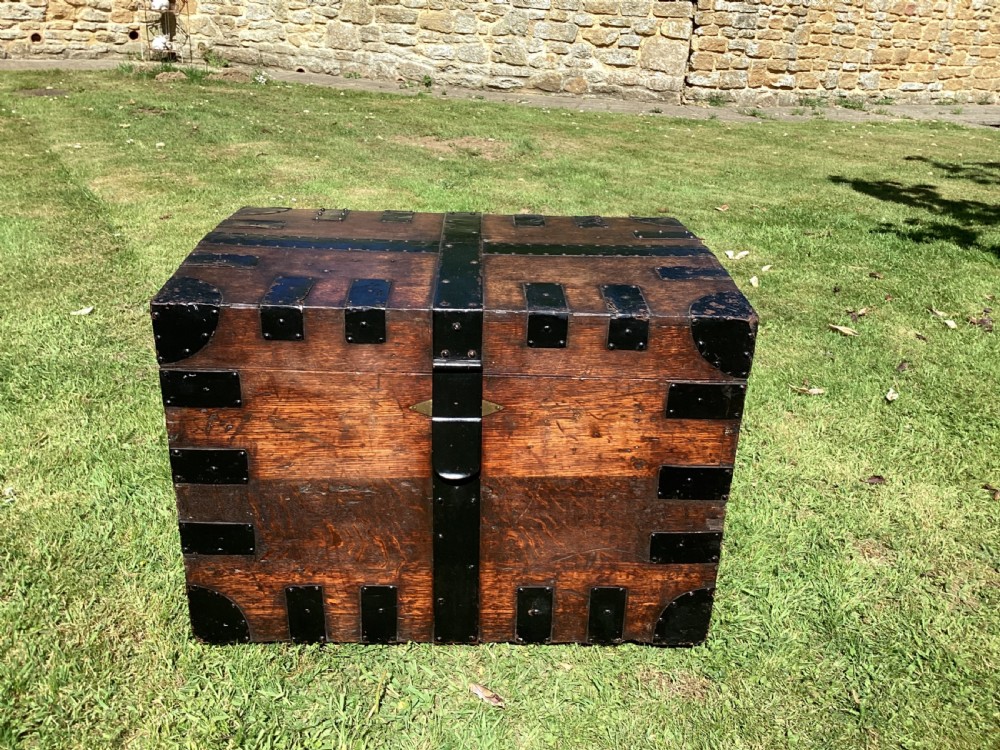 A 19th-century dark oak silver chest featuring black metal binding straps, corner plates, and central locking mechanism.
