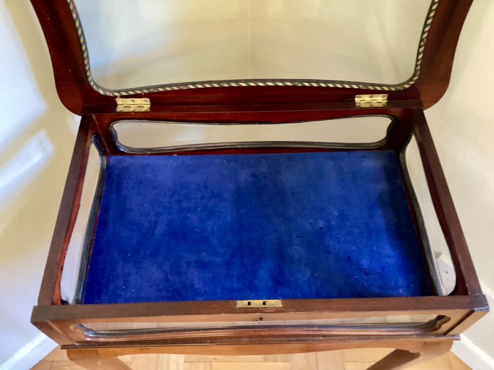 A mahogany bijouterie table featuring curved cabriole legs, glass sides, a glazed top lid, and a blue fabric lining within. View IV