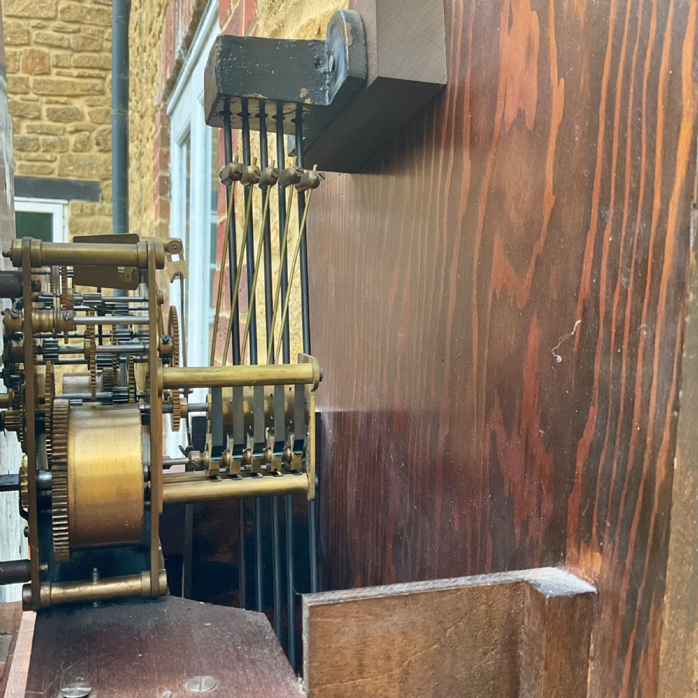 A floor-standing walnut grandmother longcase clock featuring an arched hood, brass dial with Roman numerals, long trunk door, and stepped plinth base. View XV