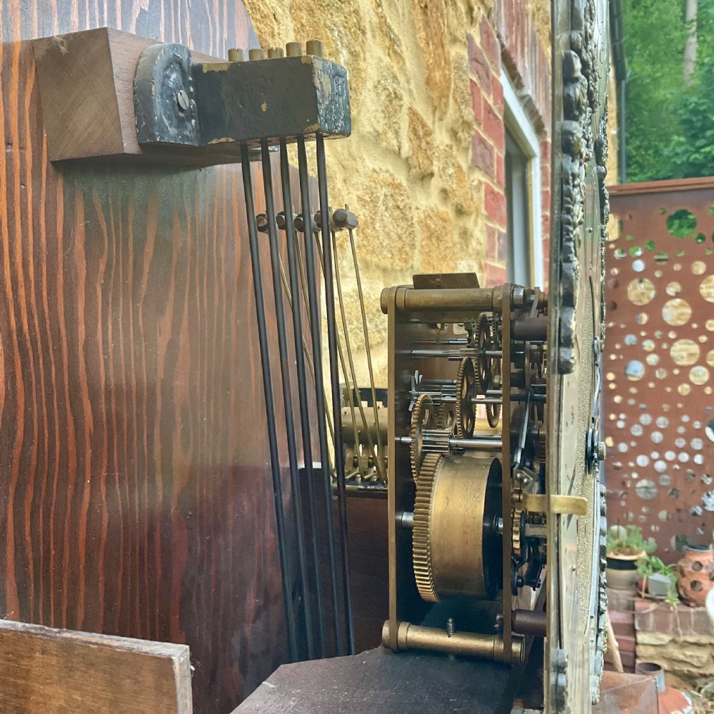 A floor-standing walnut grandmother longcase clock featuring an arched hood, brass dial with Roman numerals, long trunk door, and stepped plinth base. View XVII