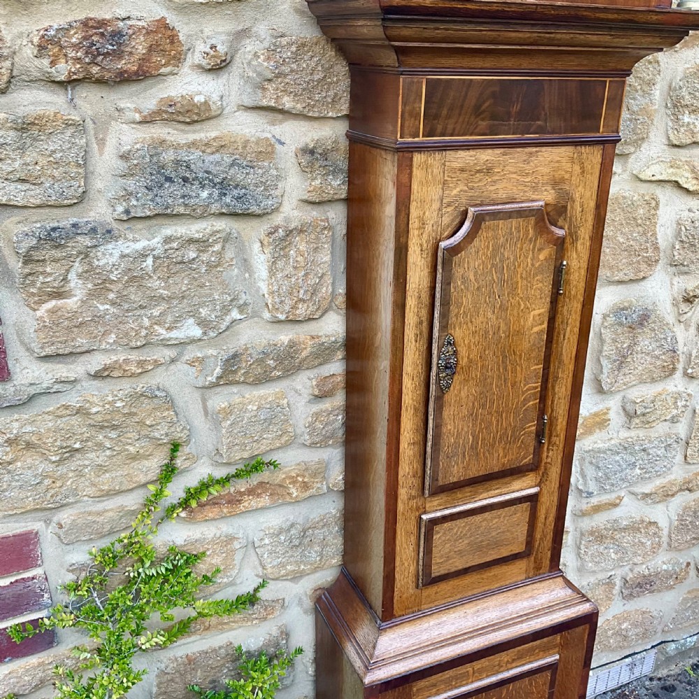 A Georgian oak and mahogany longcase clock featuring a swan-neck pediment, fluted hood columns, and a painted square dial. View IX