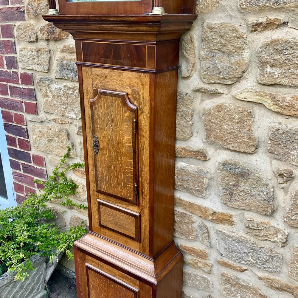 A Georgian oak and mahogany longcase clock featuring a swan-neck pediment, fluted hood columns, and a painted square dial. View XIV