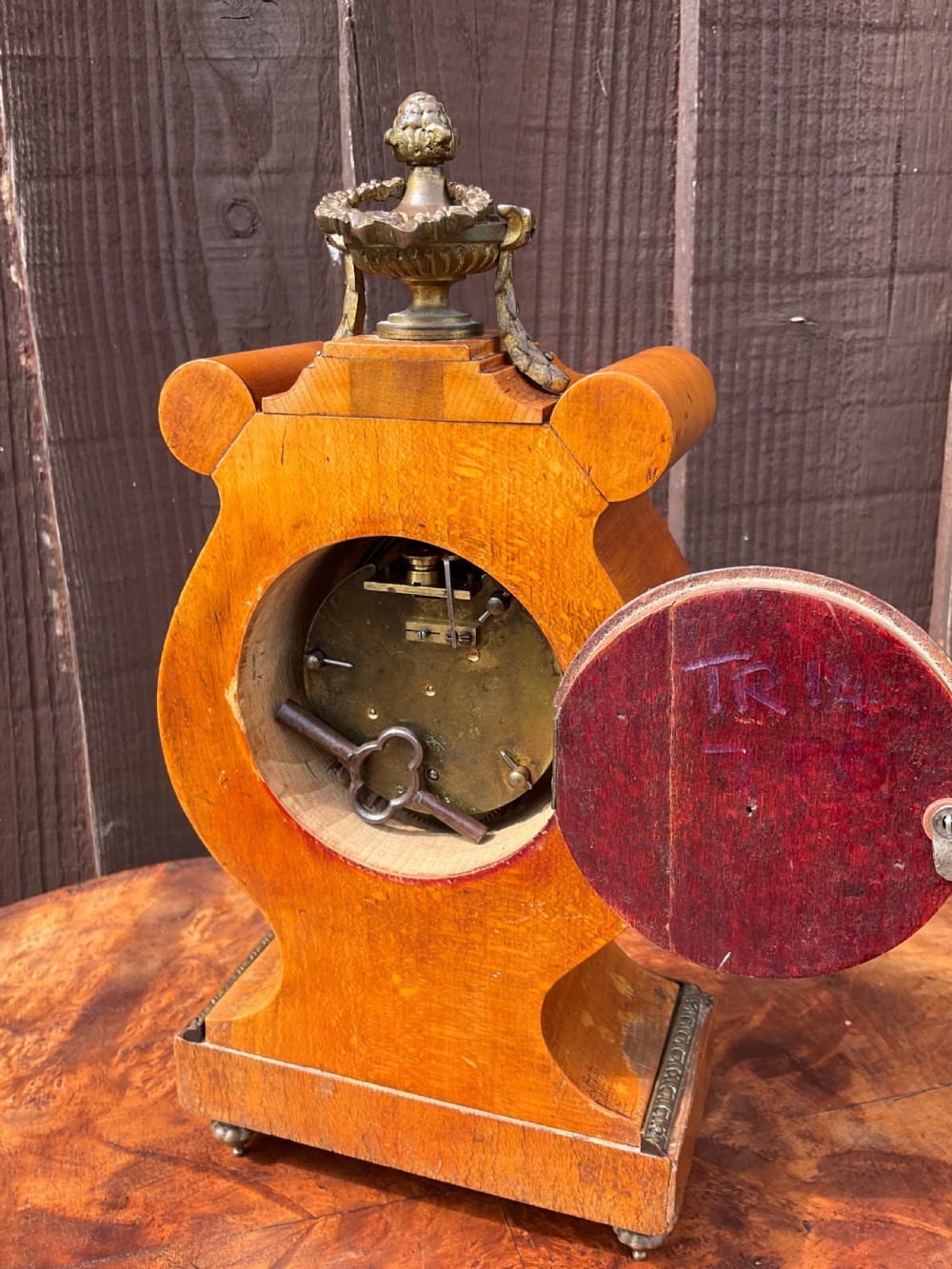 A small lyre-shaped mantel clock featuring figured burr walnut veneer, gilt ormolu swags, an urn finial, and an enamelled dial with Arabic numerals. View III