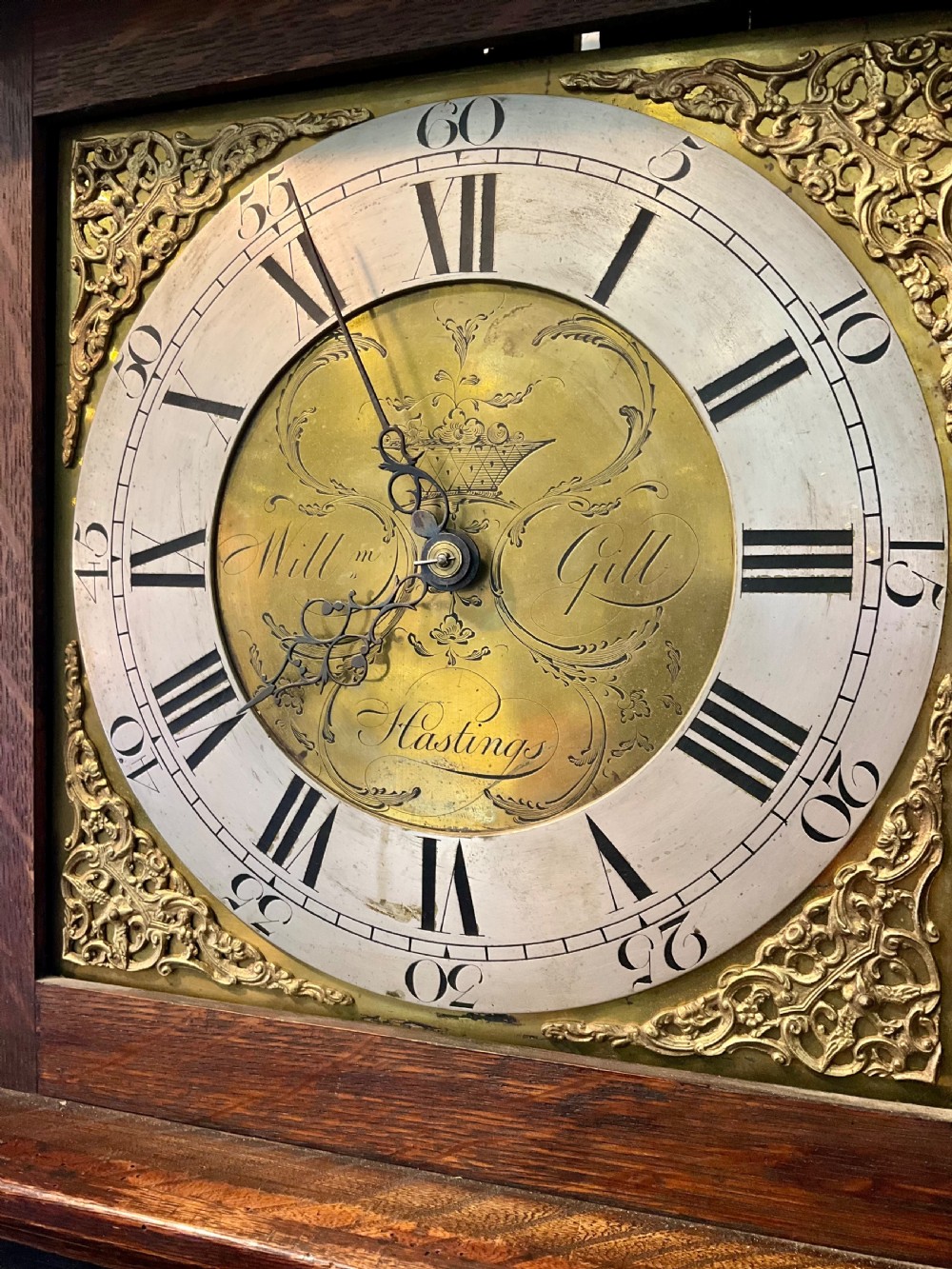 A Georgian mahogany longcase clock featuring geometric wood inlay, a brass dial with a silvered chapter ring, and turned columns flanking the hood. View V