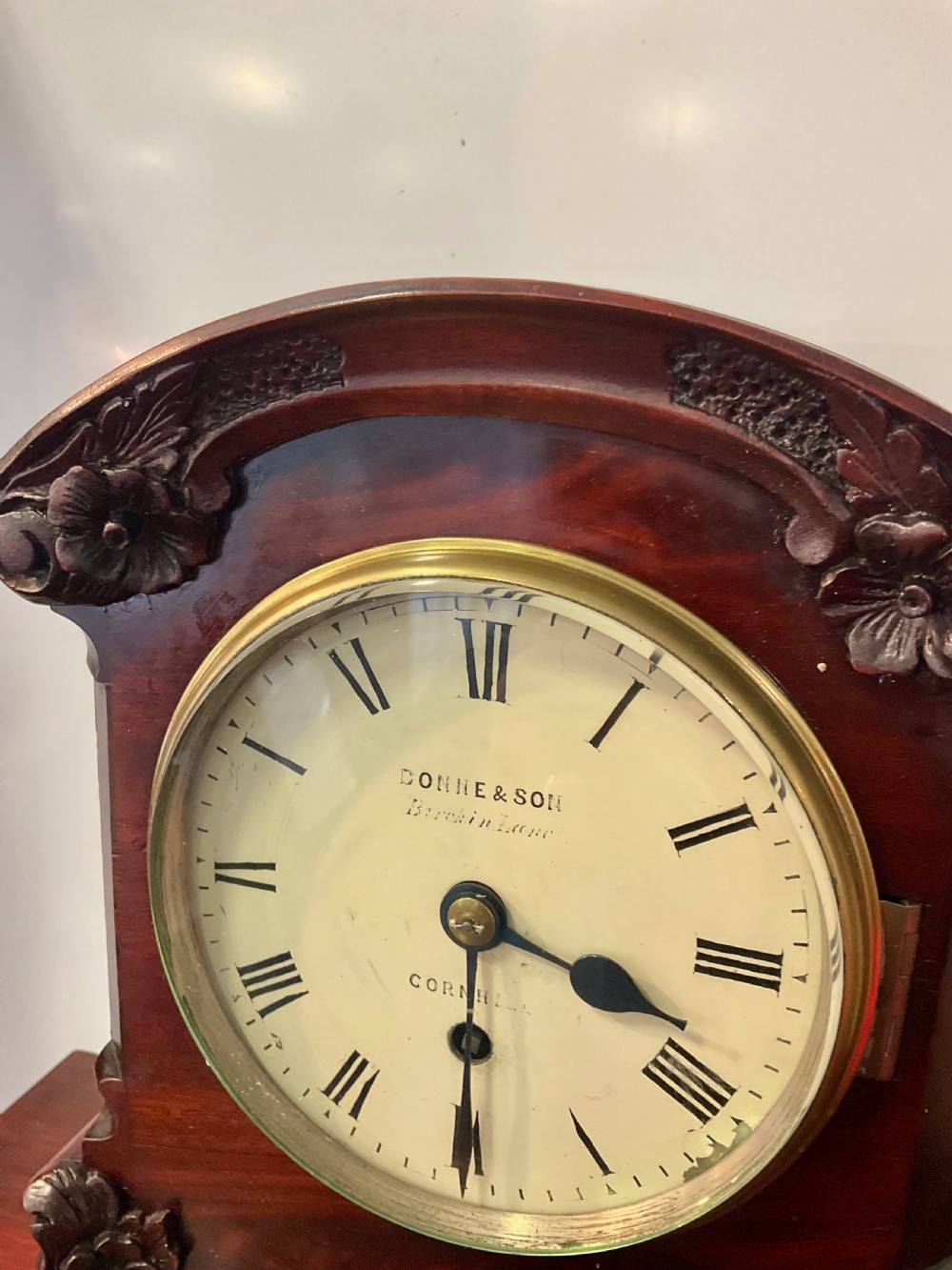 A 19th-century mahogany fusee bracket clock featuring an arched case with hand-carved floral spandrels, flame mahogany veneer, and a circular cream dial with Roman numerals. View II