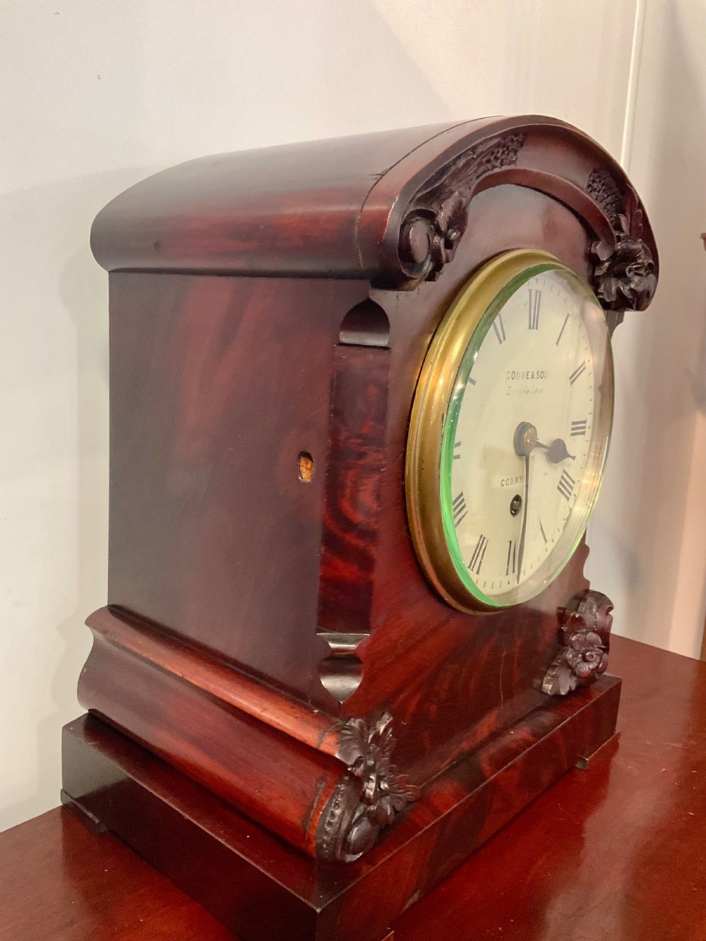 A 19th-century mahogany fusee bracket clock featuring an arched case with hand-carved floral spandrels, flame mahogany veneer, and a circular cream dial with Roman numerals. View III