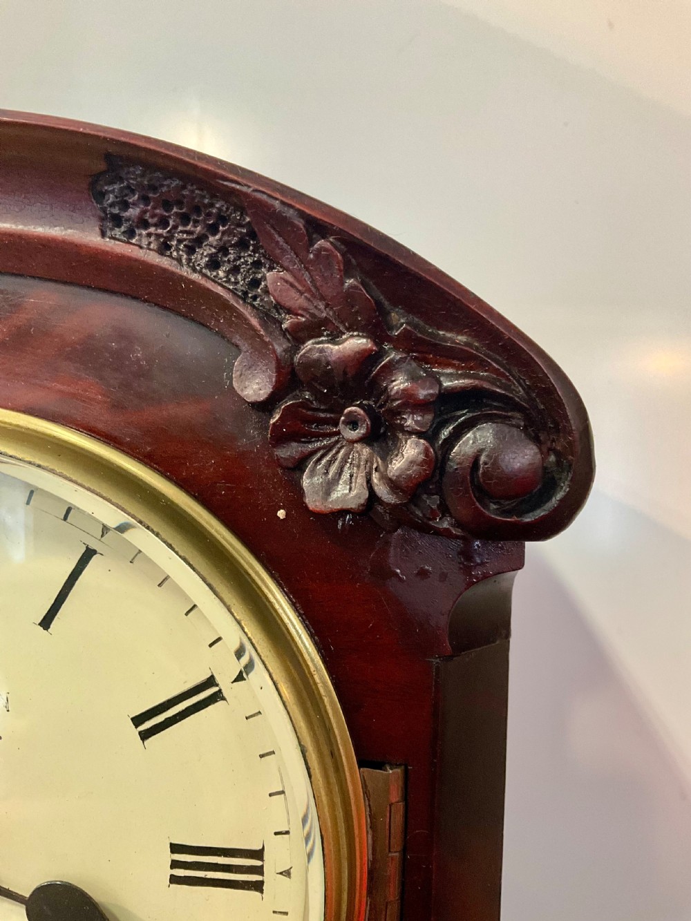 A 19th-century mahogany fusee bracket clock featuring an arched case with hand-carved floral spandrels, flame mahogany veneer, and a circular cream dial with Roman numerals. View IV