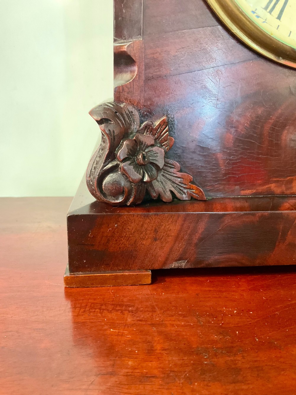 A 19th-century mahogany fusee bracket clock featuring an arched case with hand-carved floral spandrels, flame mahogany veneer, and a circular cream dial with Roman numerals. View V