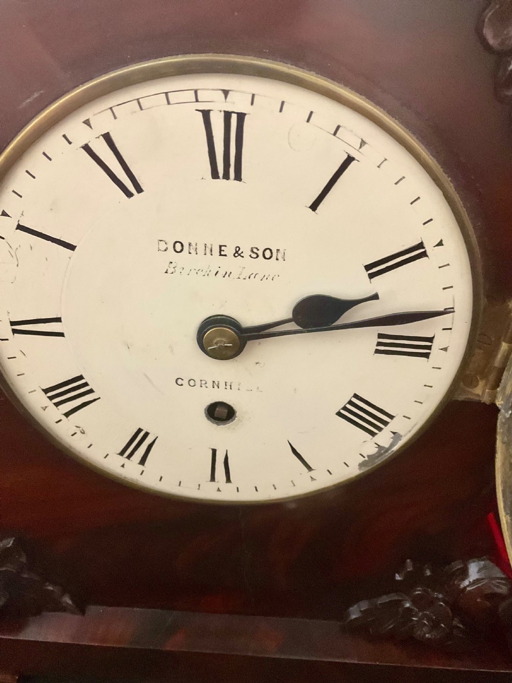A 19th-century mahogany fusee bracket clock featuring an arched case with hand-carved floral spandrels, flame mahogany veneer, and a circular cream dial with Roman numerals. View VIII