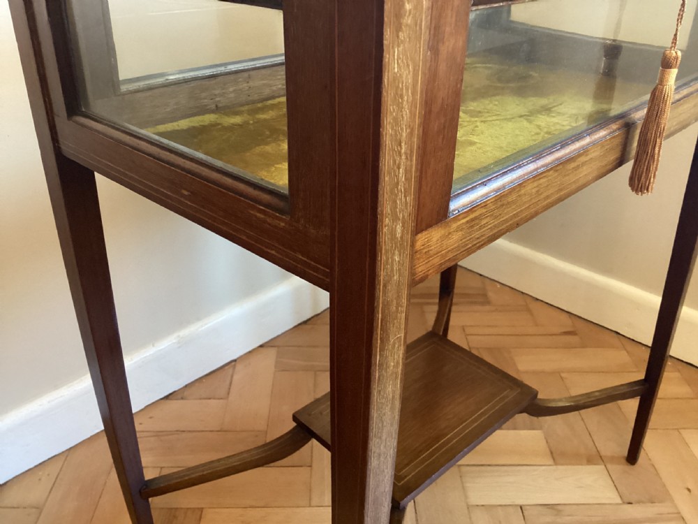An Edwardian mahogany bijouterie table with glass display panels, satinwood inlay, gold fabric lining, and tapered legs joined by an undertier. View IV