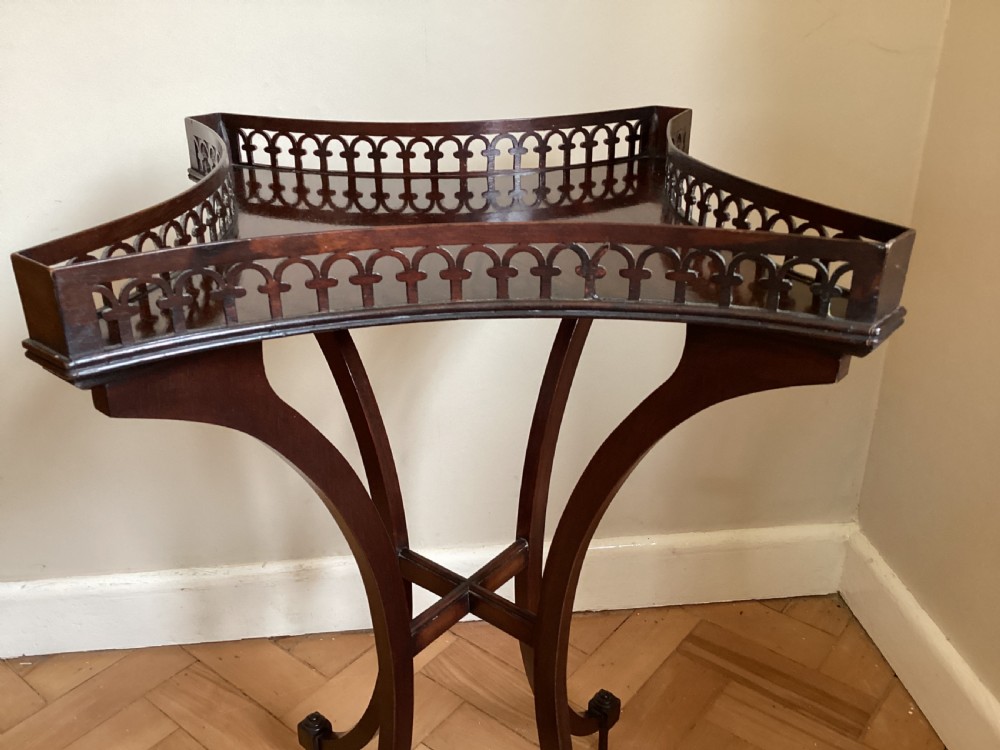 A dark mahogany occasional table featuring a concave square top surrounded by a pierced fretwork gallery, supported by four out-swept legs joined by an X-stretcher. View II