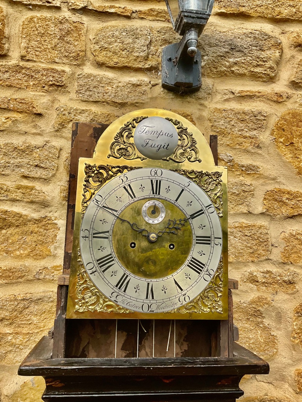 An early Georgian black japanned longcase clock featuring raised gilt Chinoiserie landscapes and figures on the case door, topped with an arched brass dial. View X