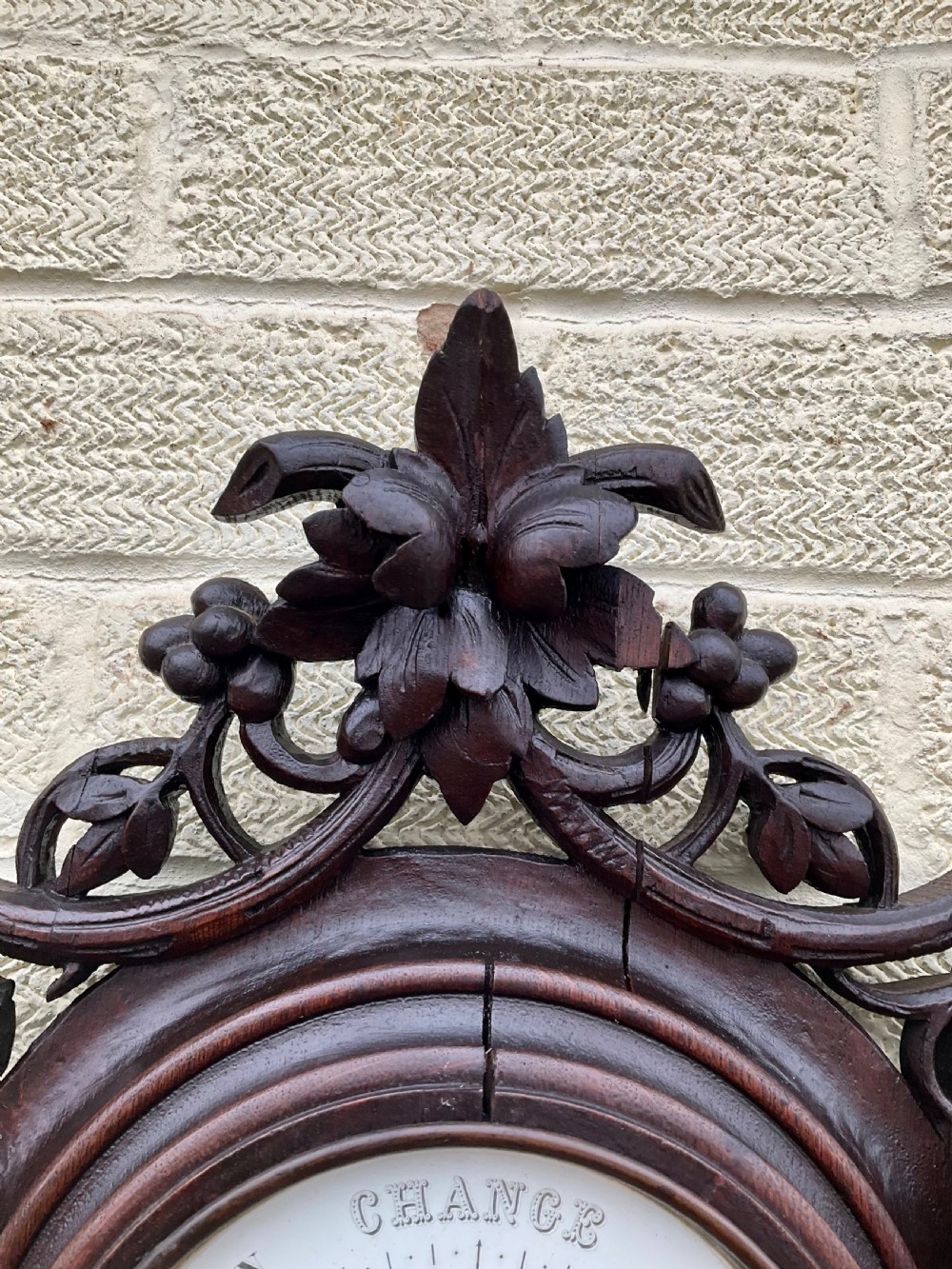 A 19th-century Black Forest aneroid barometer featuring a carved dark wood frame with leaf and acorn motifs surrounding a circular white ceramic dial. View III