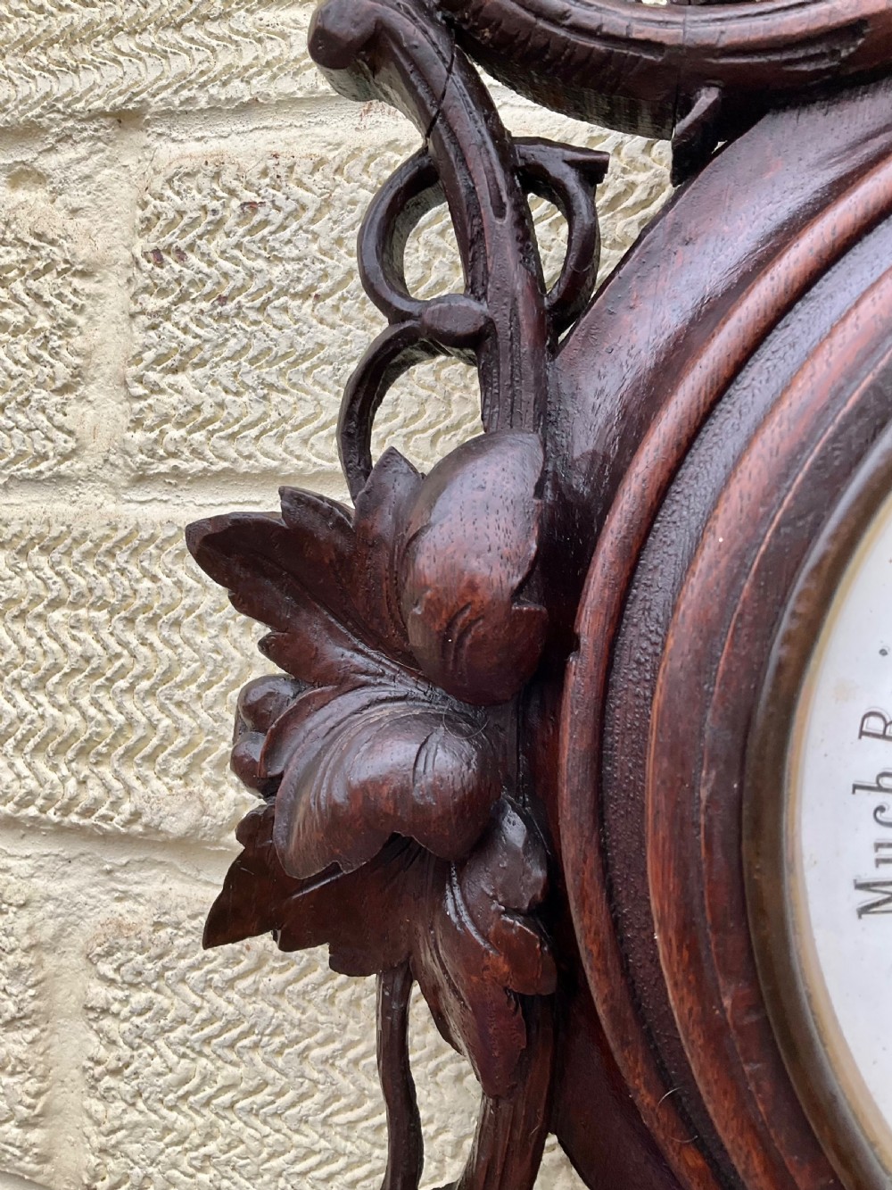 A 19th-century Black Forest aneroid barometer featuring a carved dark wood frame with leaf and acorn motifs surrounding a circular white ceramic dial. View V