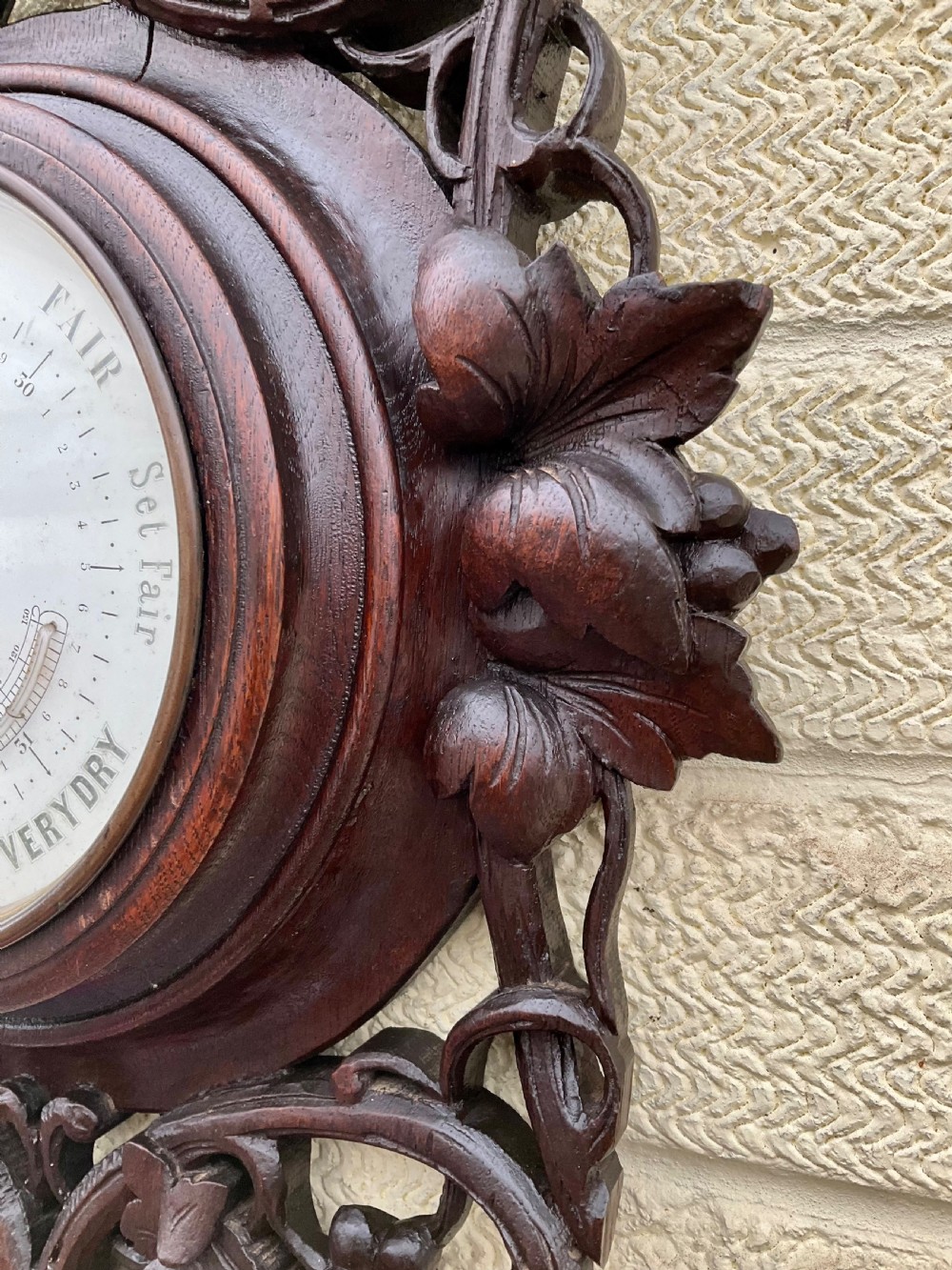 A 19th-century Black Forest aneroid barometer featuring a carved dark wood frame with leaf and acorn motifs surrounding a circular white ceramic dial. View VII