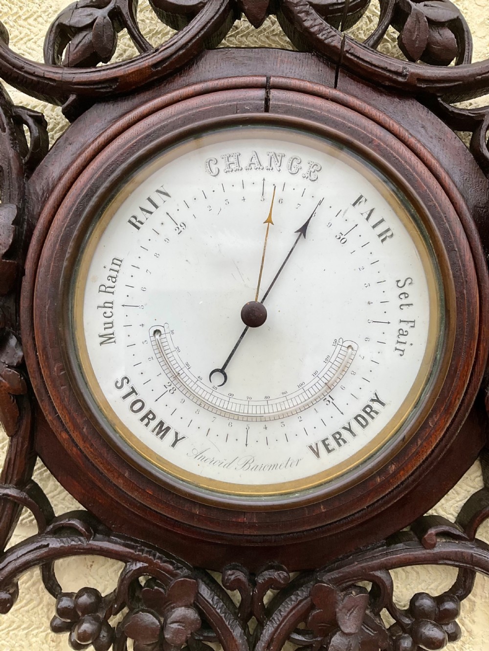 A 19th-century Black Forest aneroid barometer featuring a carved dark wood frame with leaf and acorn motifs surrounding a circular white ceramic dial. View VIII