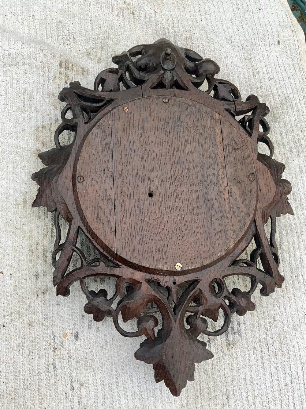 A 19th-century Black Forest aneroid barometer featuring a carved dark wood frame with leaf and acorn motifs surrounding a circular white ceramic dial. View X