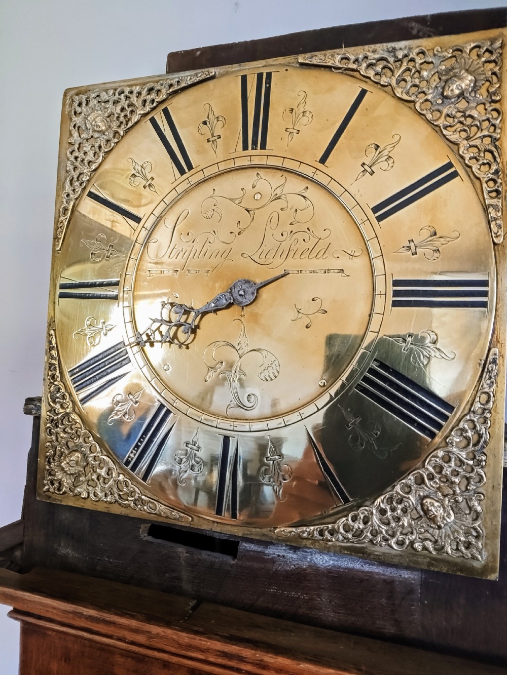 An 18th-century oak longcase clock with an eleven-inch square brass dial, turned hood columns, and a plain wooden trunk door. View VII