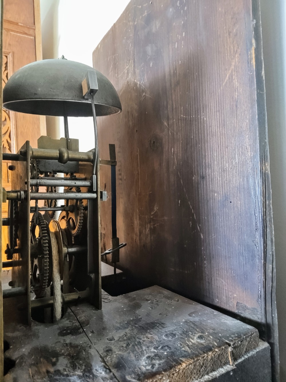 An 18th-century oak longcase clock with an eleven-inch square brass dial, turned hood columns, and a plain wooden trunk door. View XI