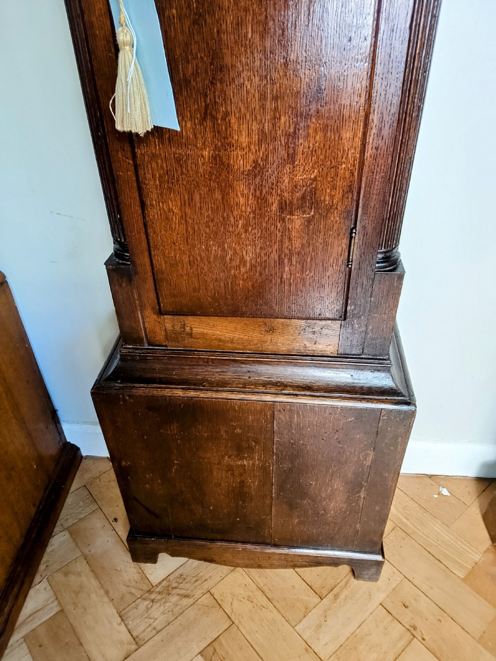 An antique Georgian dark oak grandfather clock featuring a swan-neck pediment, fluted columns, an arched trunk door, and a hand-painted floral dial. View II
