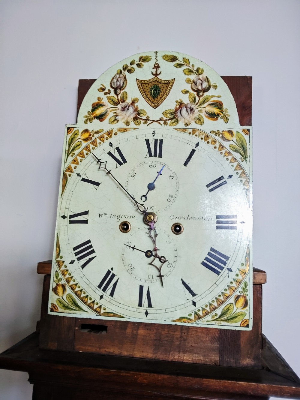 An antique Georgian dark oak grandfather clock featuring a swan-neck pediment, fluted columns, an arched trunk door, and a hand-painted floral dial. View V
