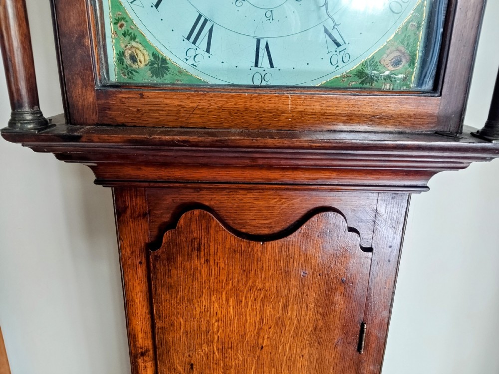 A Georgian oak and mahogany longcase clock featuring a swan-neck pediment, brass patera ornaments, fluted columns, and a painted arch dial. View III