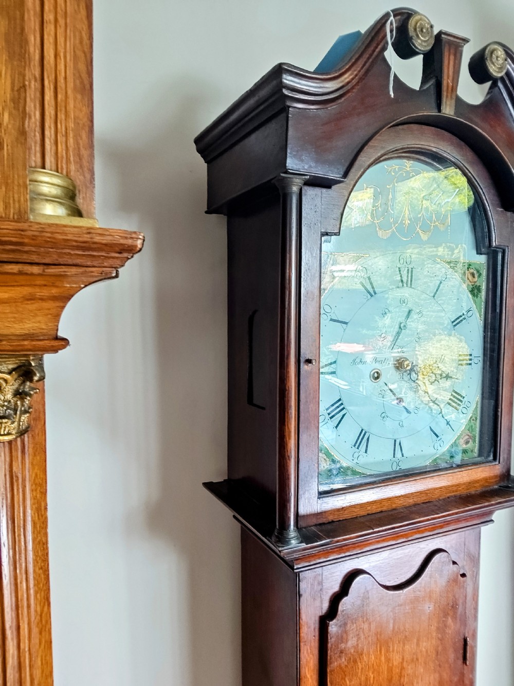 A Georgian oak and mahogany longcase clock featuring a swan-neck pediment, brass patera ornaments, fluted columns, and a painted arch dial. View VII