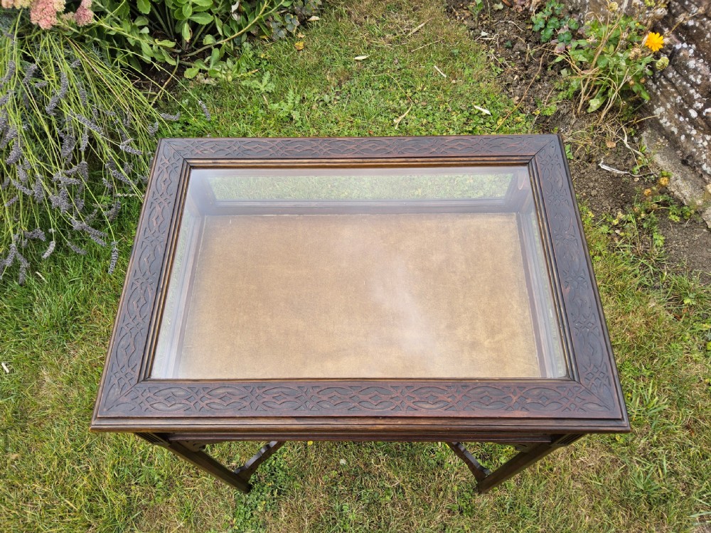 A rectangular dark mahogany bijouterie table featuring glazed sides and top, a gold fabric lining inside, pierced fretwork corner spandrels, and a lower tier shelf with a fretwork gallery. View VI