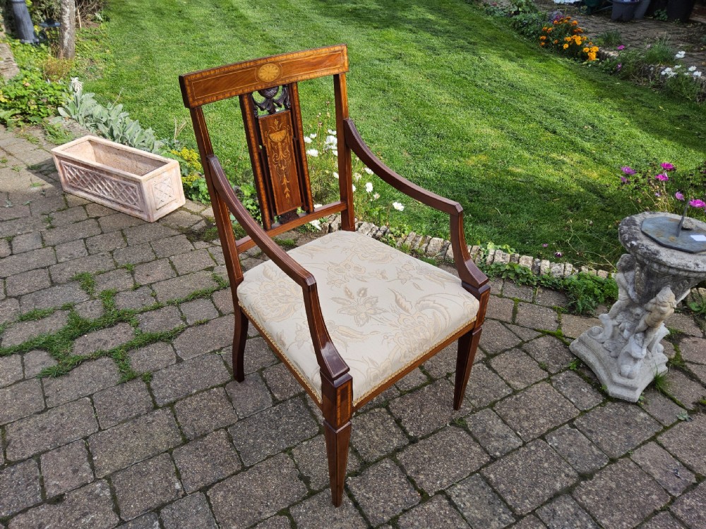An Edwardian mahogany elbow chair featuring decorative marquetry inlay on the backrest splat and a light patterned upholstered seat. View IV