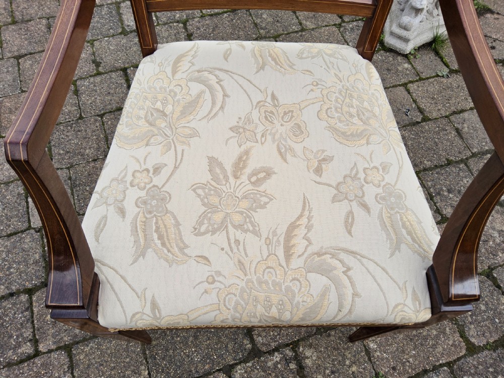 An Edwardian mahogany elbow chair featuring decorative marquetry inlay on the backrest splat and a light patterned upholstered seat. View VII
