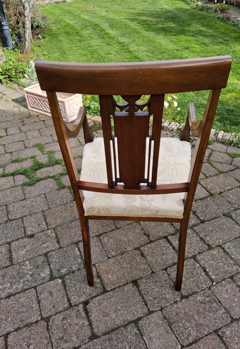 An Edwardian mahogany elbow chair featuring decorative marquetry inlay on the backrest splat and a light patterned upholstered seat. View XI