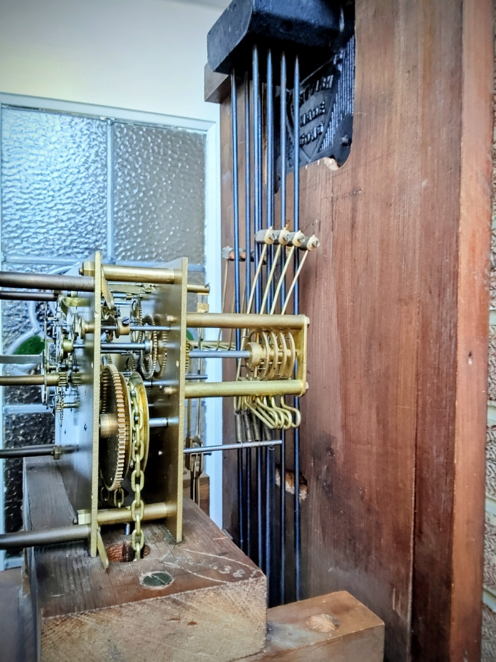 A slim mahogany grandmother longcase clock with a carved top frieze, brass Roman numeral dial, and an arched waist door. View X