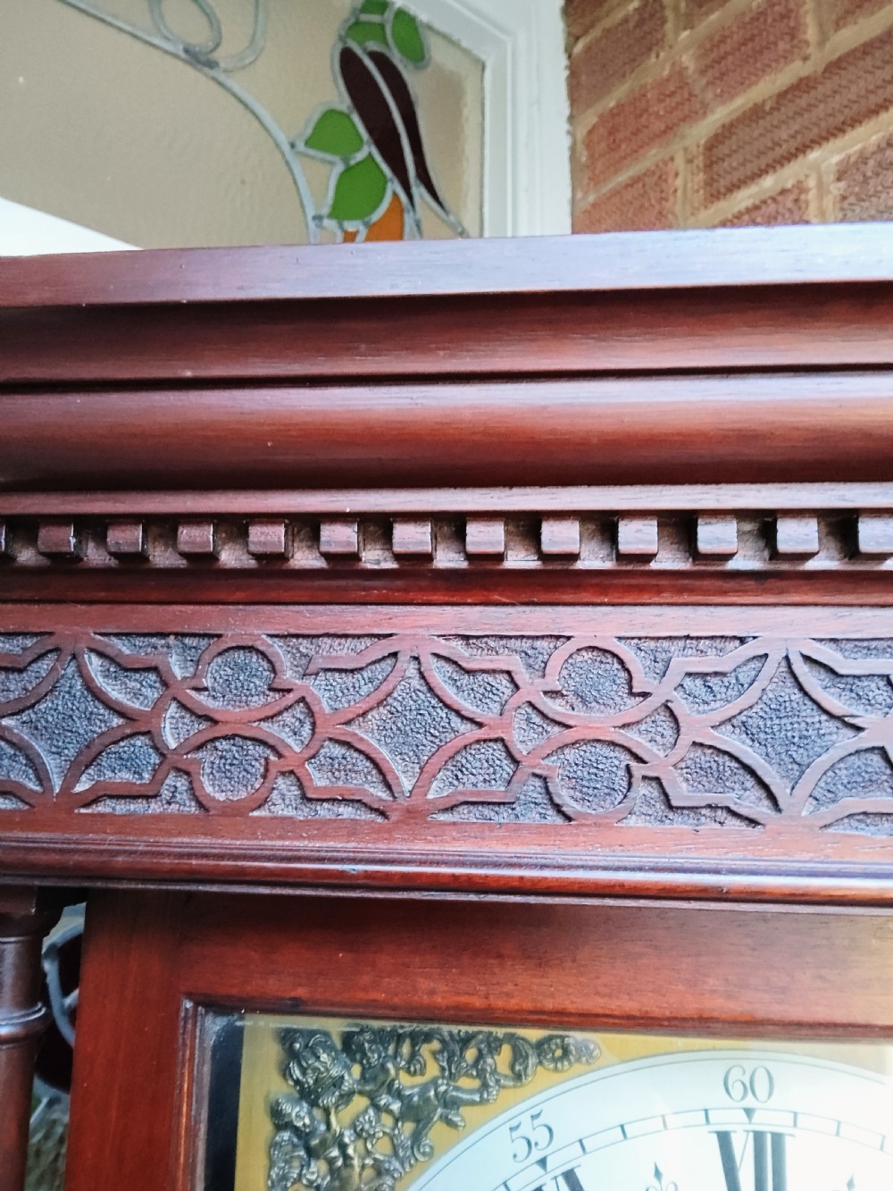 A slim mahogany grandmother longcase clock with a carved top frieze, brass Roman numeral dial, and an arched waist door. View XV