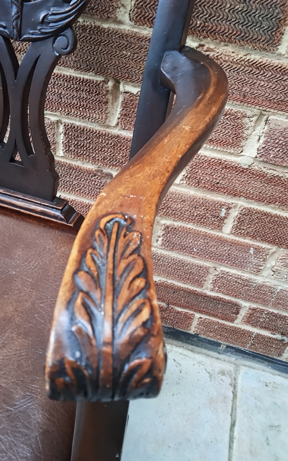 A dark mahogany elbow chair featuring a carved pierced splat back, shaped arms, a brown leather seat, and cabriole legs with ball and claw feet. View III