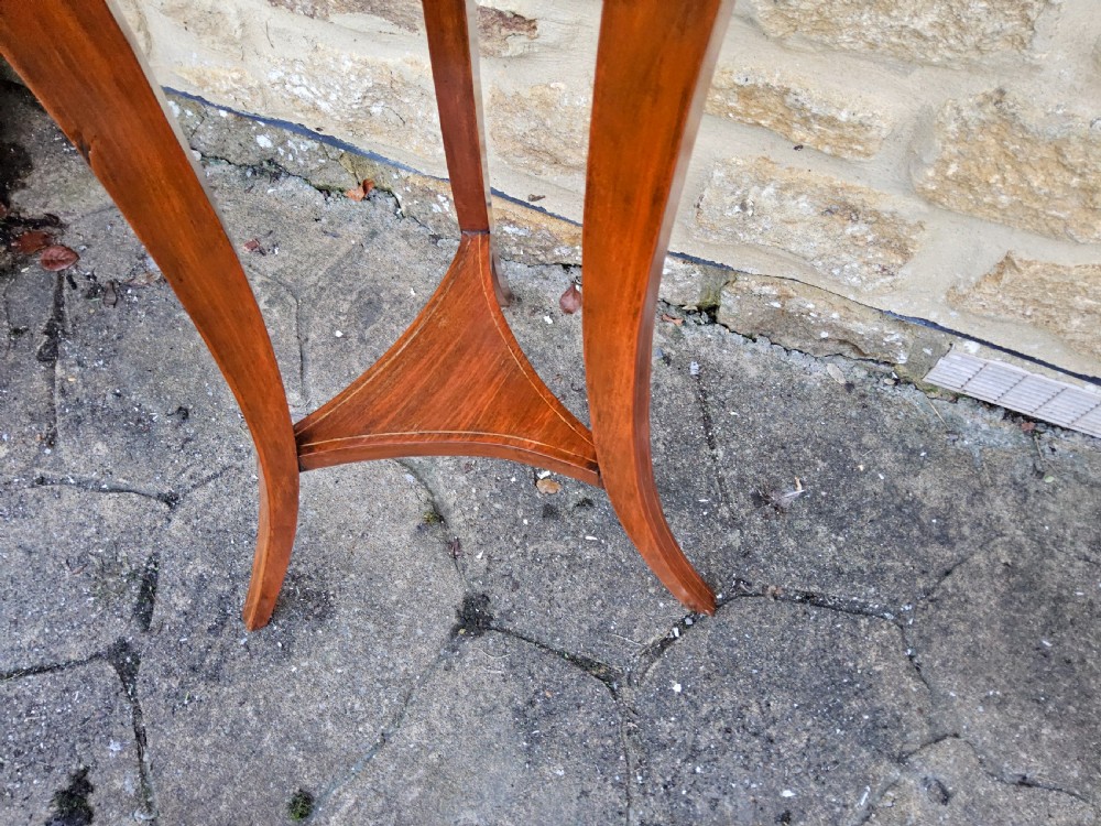 An Edwardian mahogany tripod jardiniere stand featuring slatted sides, satinwood stringing inlay around the top rim, three sweeping splayed legs, and a removable metal liner. View VI