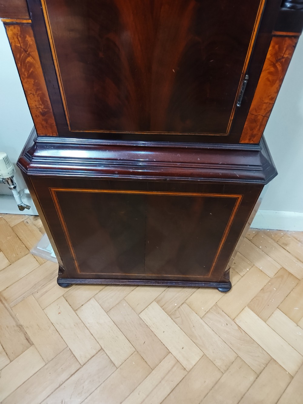A Georgian flame mahogany longcase clock featuring a painted dial with moon phase indicator, swan-neck pediment, brass finials, and fluted columns. View XVI