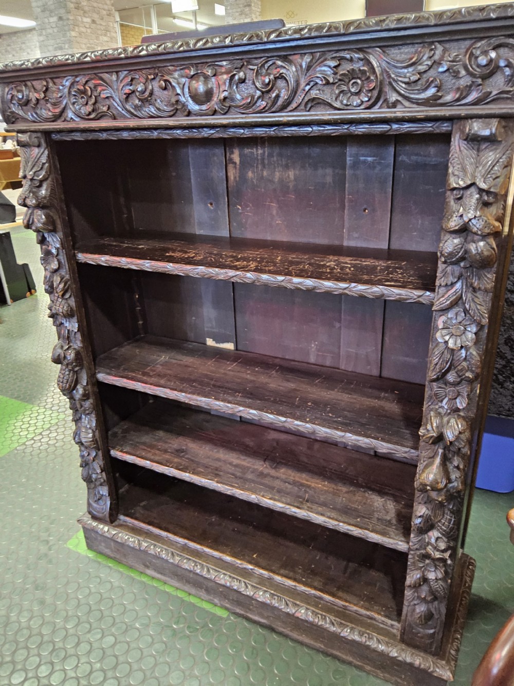 A dark oak Victorian open bookcase featuring hand-carved floral friezes, fruit garlands along the side columns, and adjustable shelving. View II