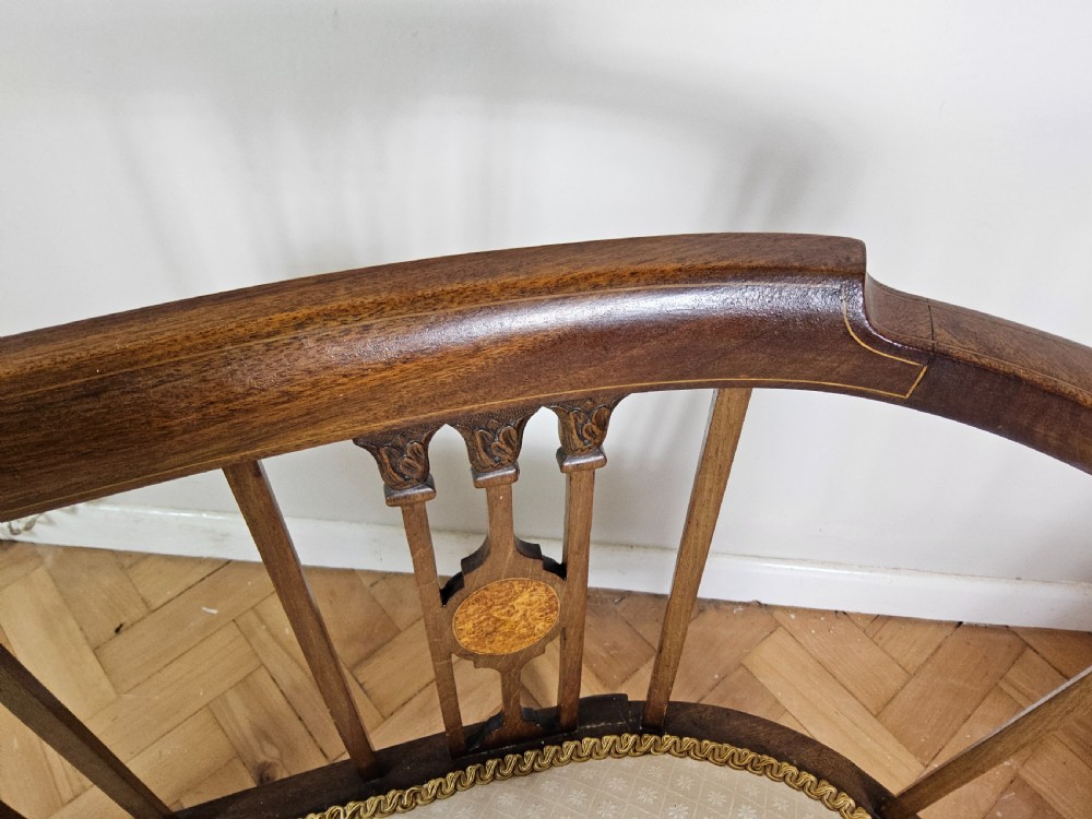 An Edwardian mahogany settee featuring a curved backrest with inlaid vertical splats, tapered legs, and a cream patterned upholstered seat. View II