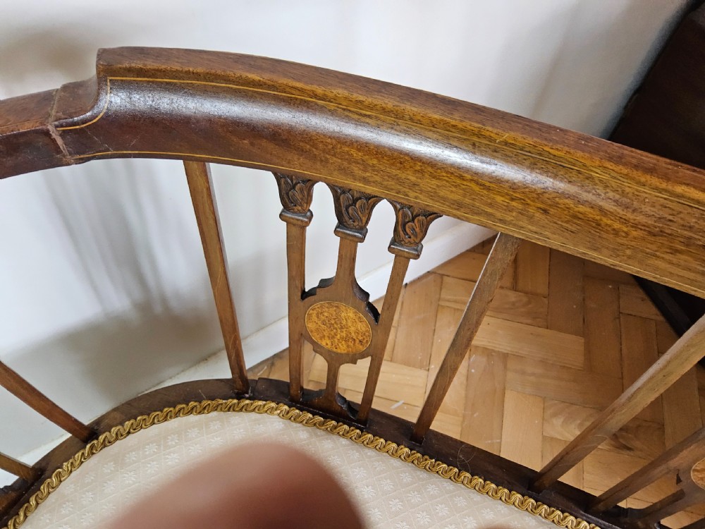 An Edwardian mahogany settee featuring a curved backrest with inlaid vertical splats, tapered legs, and a cream patterned upholstered seat. View III
